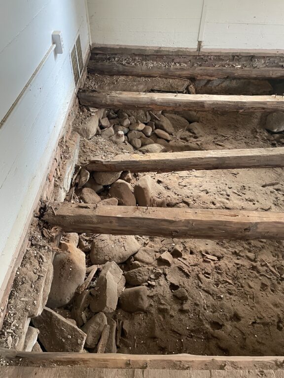 Renovation of school floor with exposed wooden beams and debris, preparing for new flooring installation in Croydon School District.
